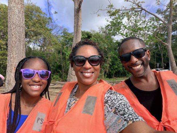 The three of us in orange life jackets, sunglasses on, with trees and open sky behind us